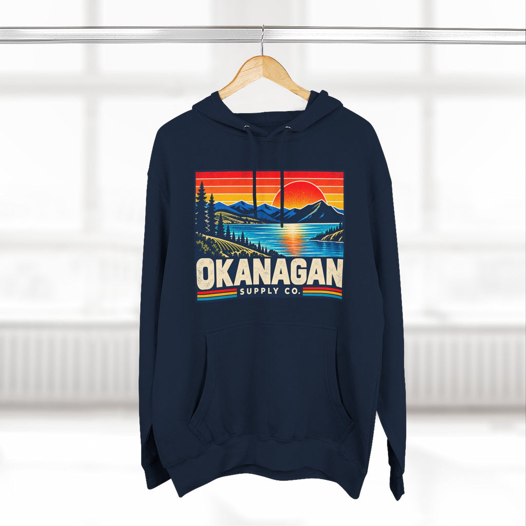 Okanagan Supply Co. Retro Sunset Hoodie in navy, hanging on a rack