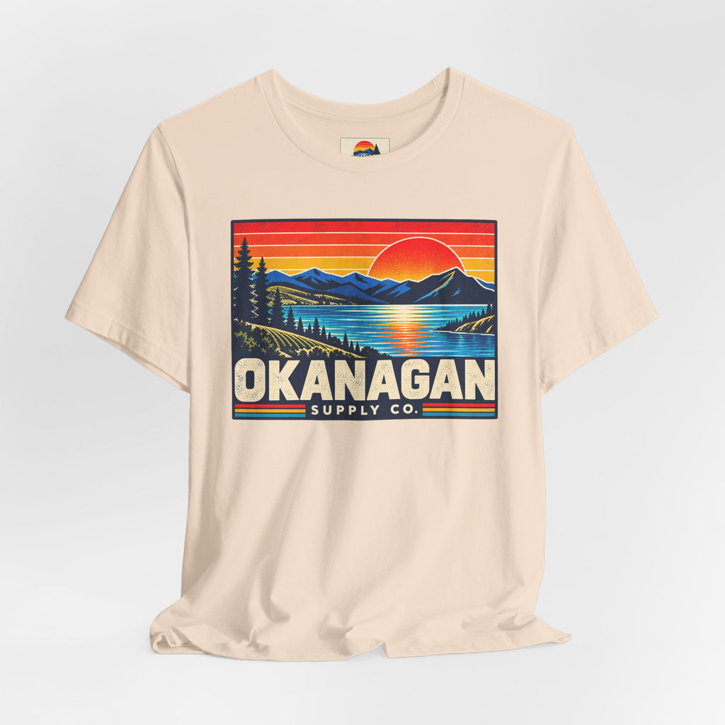 Okanagan Supply Co. Retro Sunset Tee in soft cream, styled flat view with sunset badge