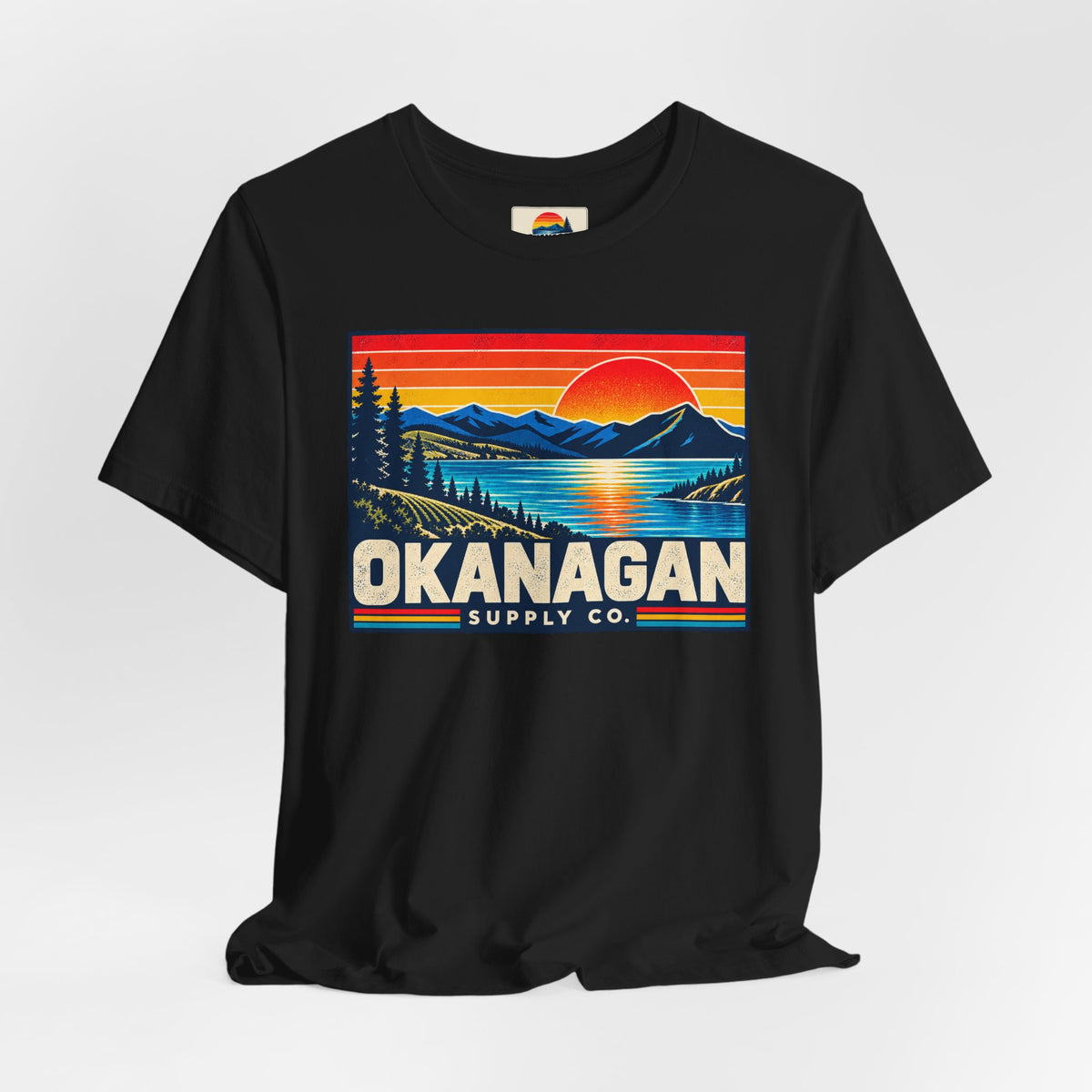 Okanagan Supply Co. Retro Sunset Tee in black, styled flat view with sunset badge