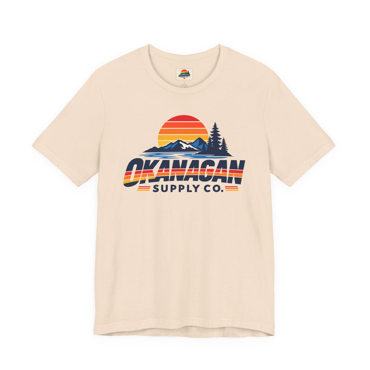Okanagan Supply Co. Vintage Outdoors Tee in soft cream, front view with retro sunset, mountain and pine print