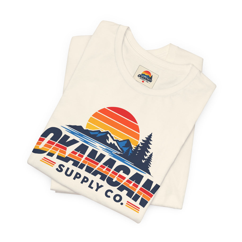 Okanagan Supply Co. Vintage Outdoors Tee in natural, folded to show the retro sunset, mountain and pine print and inside collar label