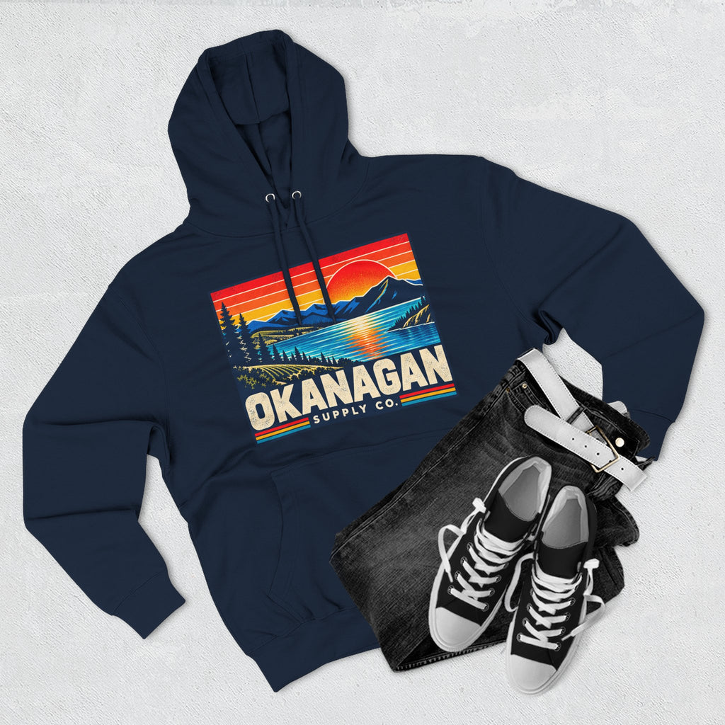 Okanagan Supply Co. Retro Sunset Hoodie in navy, flat lay with jeans and sneakers