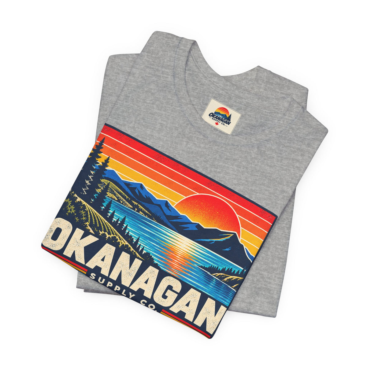 Okanagan Supply Co. Retro Sunset Tee in athletic heather, folded to show the sunset badge print and inside collar label