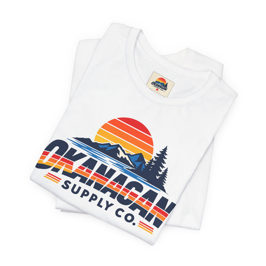 Okanagan Supply Co. Vintage Outdoors Tee in white, folded to show the retro sunset, mountain and pine print and inside collar label