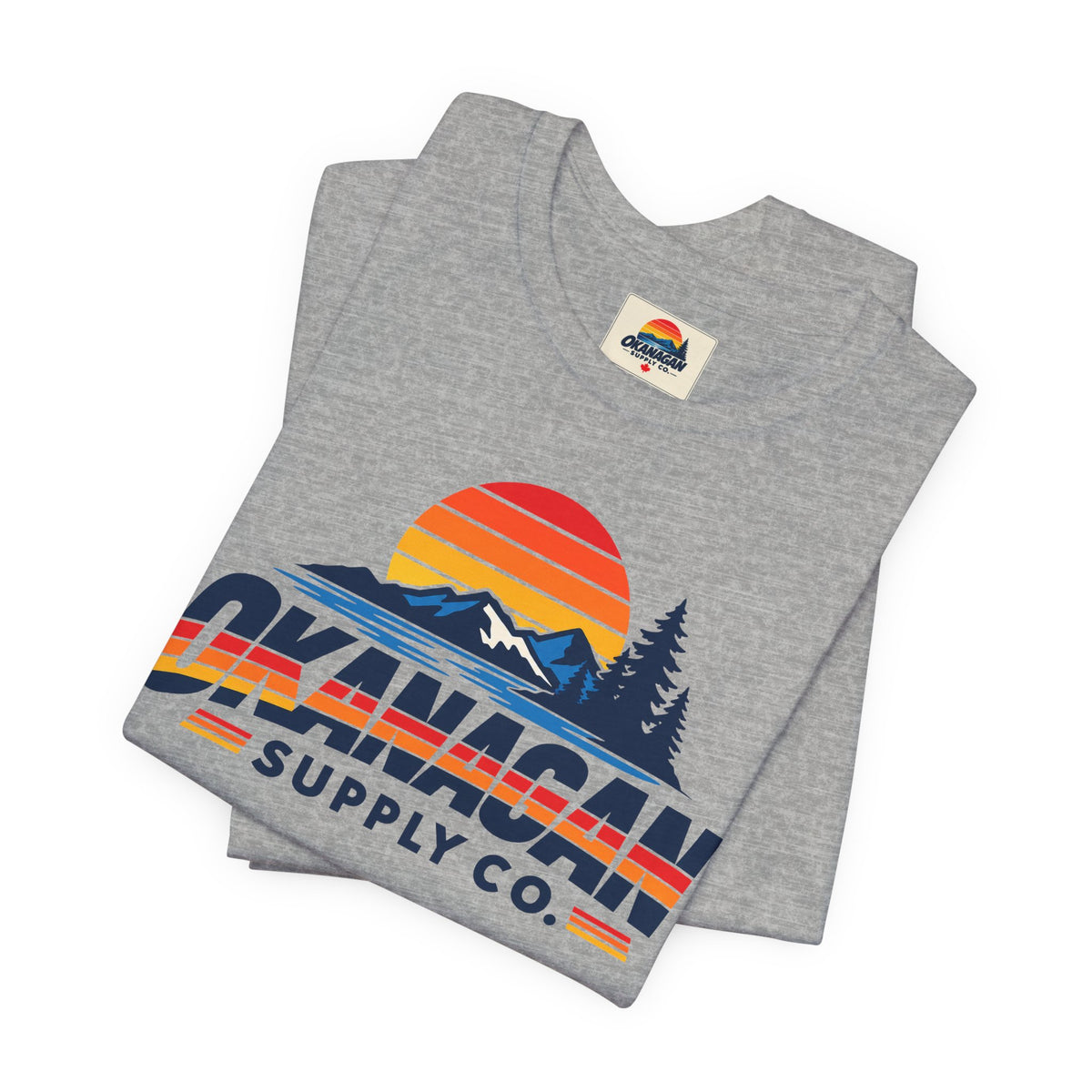 Okanagan Supply Co. Vintage Outdoors Tee in athletic heather, folded to show the retro sunset, mountain and pine print and inside collar label