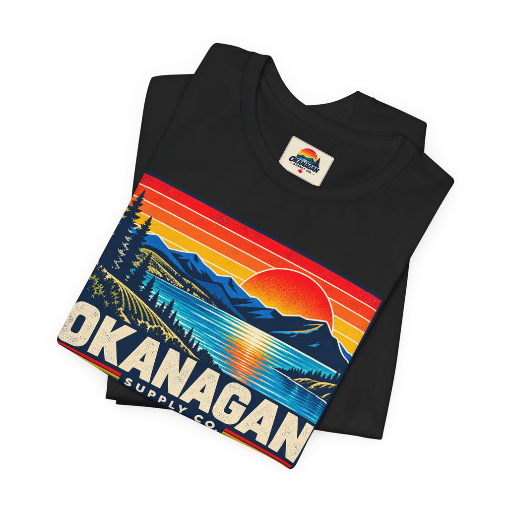 Okanagan Supply Co. Retro Sunset Tee in black, folded to show the sunset badge print and inside collar label